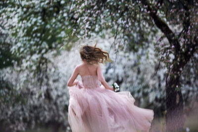 Rear view of woman standing against trees