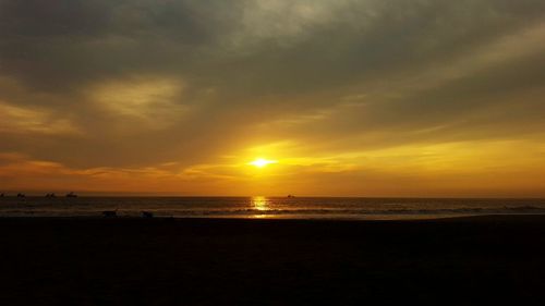 Scenic view of sea against dramatic sky during sunset