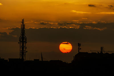Silhouette tower and buildings against sky during sunset