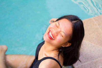 Close up asian woman smiling while is sitting down near by pool