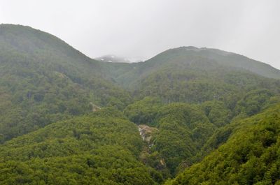 Scenic view of green landscape and mountains against sky