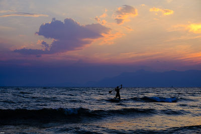 Silhouette man standing on sea against sky during sunset