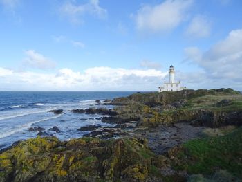 Lighthouse by sea against sky