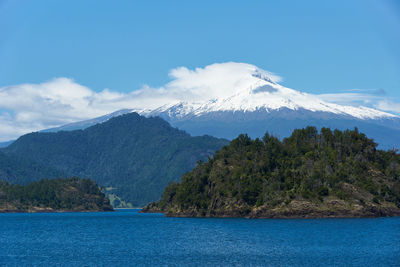 Scenic view of sea by mountain against sky