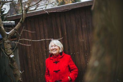 Portrait of senior woman standing by tree trunk