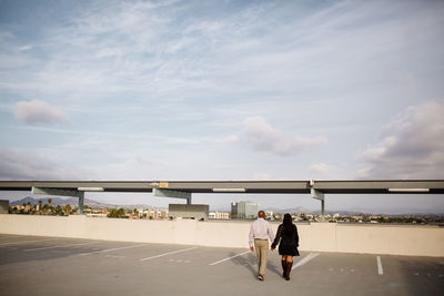 Rear view of people walking on road against sky