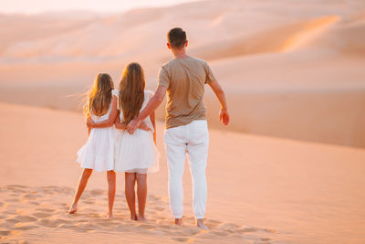 Rear view of father with daughters at desert