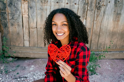 Portrait of smiling young woman holding heart shape