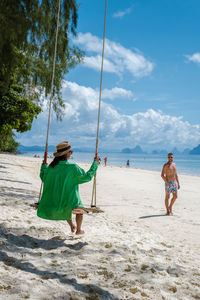 Rear view of woman swinging at beach