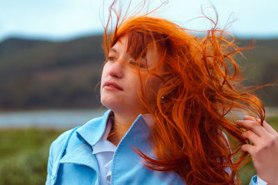 Close-up of young woman with tousled hair at lakeshore