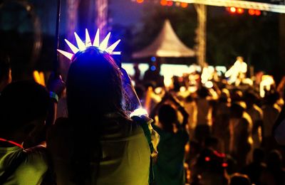 Rear view of woman wearing illuminated crown at night