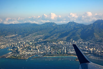 Aerial view of city by sea against sky