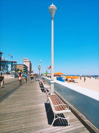 People walking on beach against clear blue sky