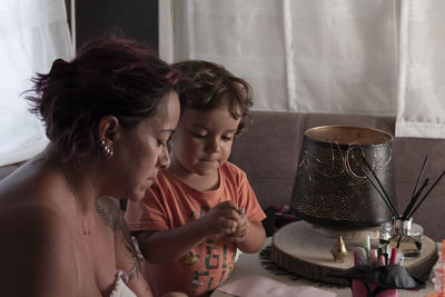 Mother and 3-year-old caucasian son make crafts in caravan while on vacation