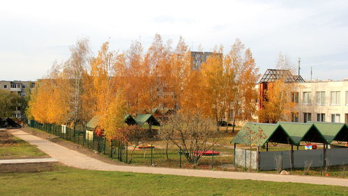 Park by buildings against sky during autumn