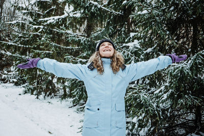 Hello winter, happy wintertime. happy young curly woman with hands raised up celebrating winter