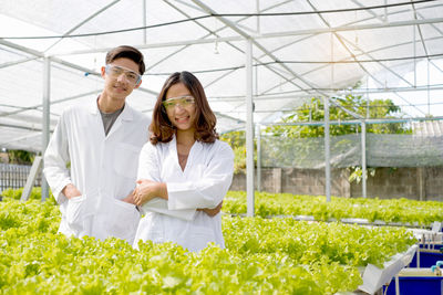 Smiling young woman standing in greenhouse