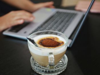 Cropped image of hand holding coffee cup on table