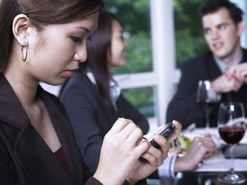 Businesswoman using smart phone at restaurant during meeting
