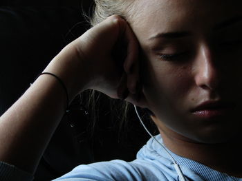 Close-up of young woman listening music on headphones