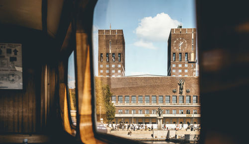 Buildings against sky seen through window