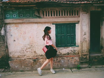 Young woman standing in front of house