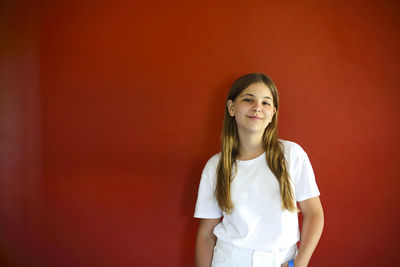 Portrait of smiling girl against red wall