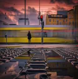 Railroad station platform against sky during sunset