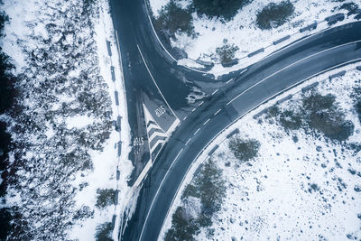Aerial view of road amidst snow covered fields