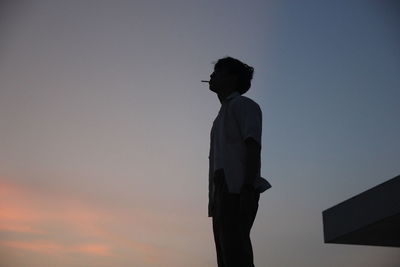 Rear view of man standing against sky during sunset