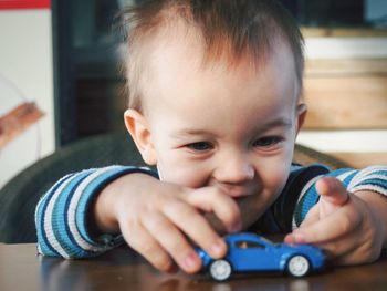 Cute boy playing with toy car at home