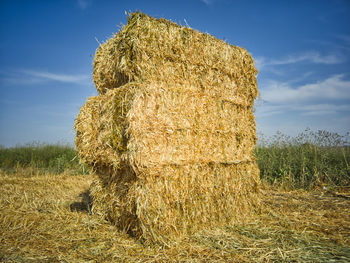 Hay bales on field against sky