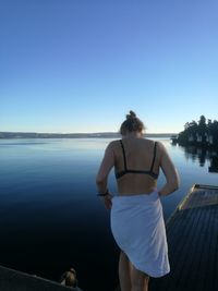 Rear view of woman standing against lake