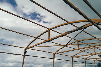 Low angle view of electricity pylon against cloudy sky