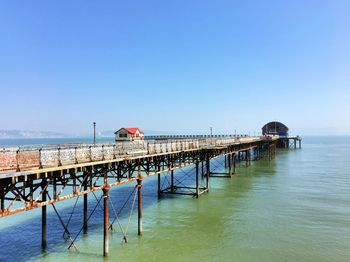 Pier over sea against clear blue sky