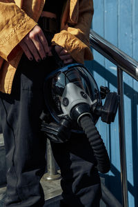 Midsection of woman holding gas mask outdoors