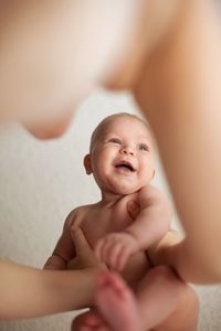 Cropped hands of mother lifting baby boy