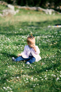 Cute girl sitting on grass in field