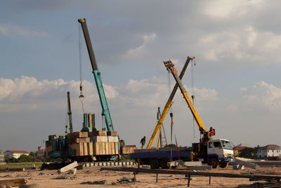 Cranes at construction site against sky