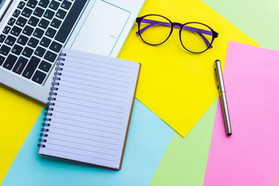 Spiral notebook with laptop on colorful papers