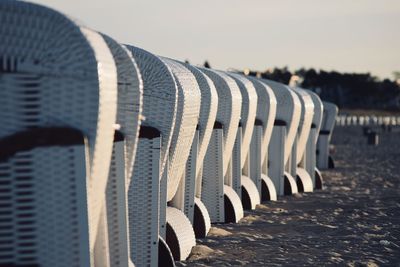 Hooded chairs at beach against sky during sunset