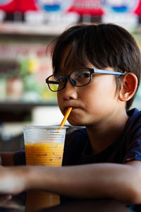 Portrait of boy drinking juice on table in cafe