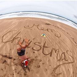 High angle view of man doing handstand on sand at beach during christmas