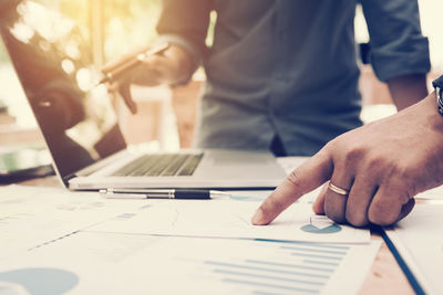 Midsection of businessmen working over graph on table