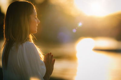 Woman meditating by the lake. prayer position.