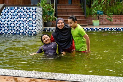 Happy family swimming in the pool. mother wearing hijab with children.