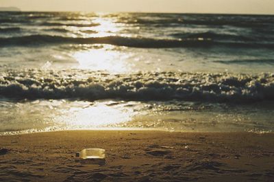 Close-up of beach against sky during sunset