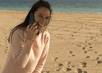 Happy woman talking over mobile phone at beach