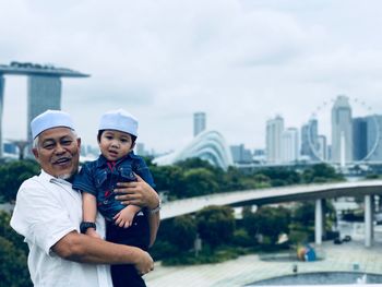 Portrait of smiling young couple in city against sky