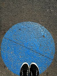 Low section of person standing against blue wall